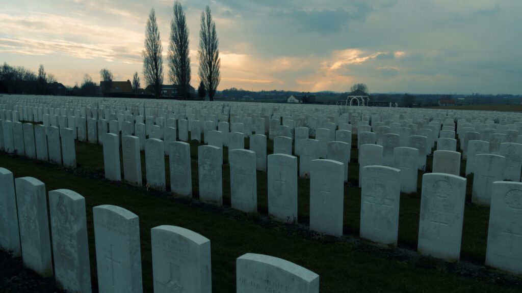Rows of gravestones in a WWI cemetery in Flanders during sunset, reflecting solemn remembrance.